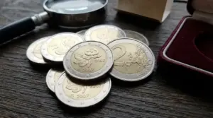 Monete da 2 euro Finlandia 2007 commemorative su tavolo in legno con lente d’ingrandimento e cofanetto