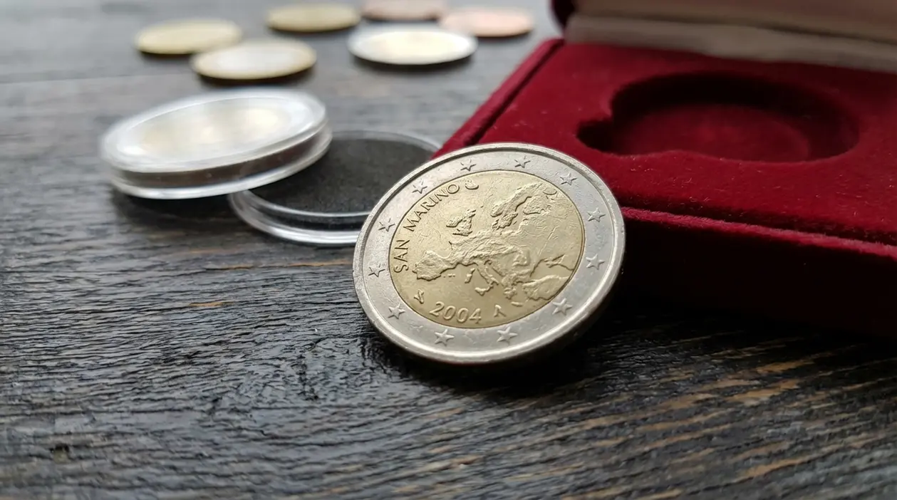 Moneta da 2 euro di San Marino 2004 su tavolo in legno, con capsule trasparenti e astuccio in velluto rosso