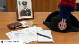 Cappello dei carabinieri su una scrivania con buste paga, banconote e monete, taccuino e portafoglio