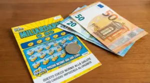 Gratta e vinci su un tavolo con banconote in euro e una moneta, per parlare di tasse sulle vincite