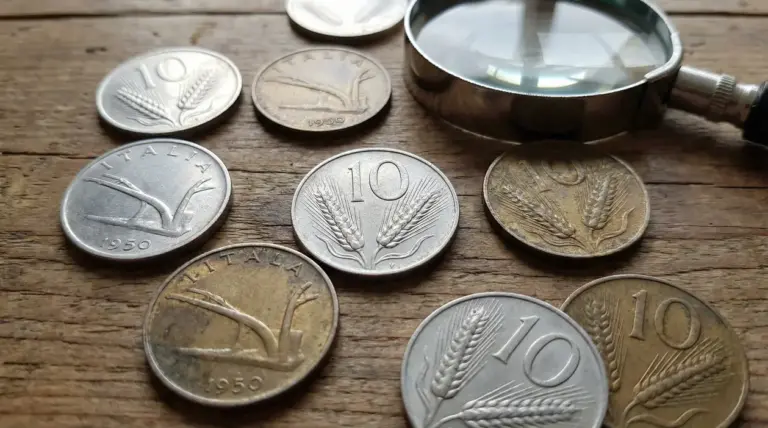 Monete italiane da 10 lire con la spiga su un tavolo, con lente d’ingrandimento per valutarne lo stato