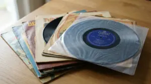 Pila di dischi in vinile con copertine vintage su un tavolo, uno in primo piano nella busta protettiva